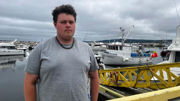 Un jeune homme debout à un port de pêche.