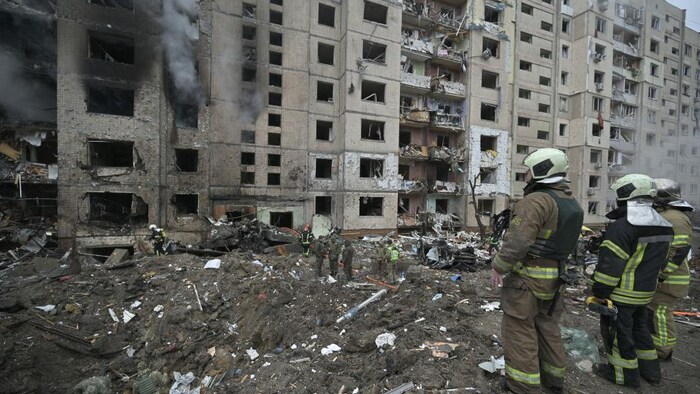 Des pompiers devant un immeuble résidentiel détruit par un bombardement.