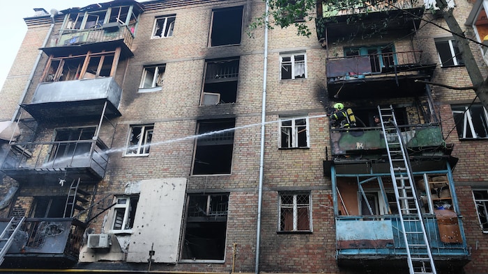 Un pompier intervient sur le site d'un immeuble résidentiel endommagé lors d'une frappe de drone russe à Kiev le 7 octobre 2026.