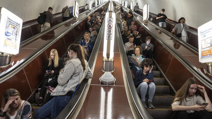 Des femmes sont assises dans un escalier mobile.