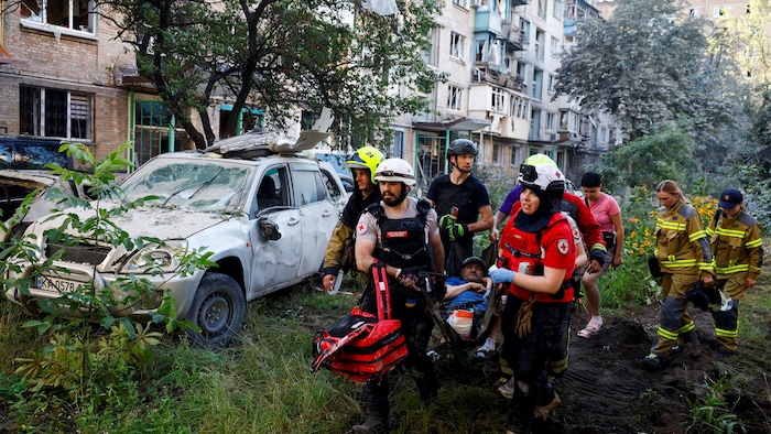 Des bénévoles, des ambulanciers et des secouristes transportent un habitant blessé sur le site d'un immeuble d'habitation endommagé à Kiev, en Ukraine, le 2 juillet 2026. 