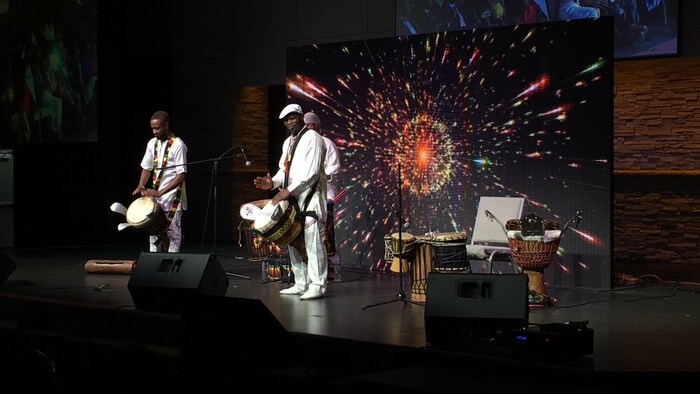 Trois hommes sur scène jouent de la musique africaine.