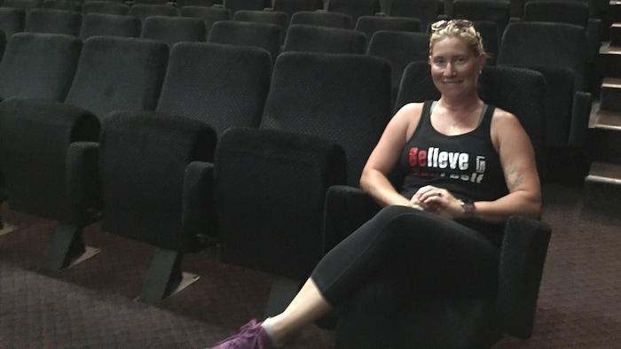 Killy-Ann Brunet assise seule dans une petite salle de cinéma vide.