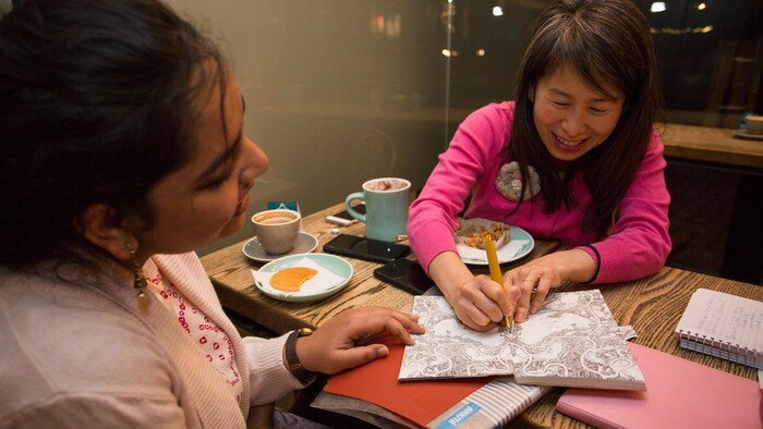 Les deux femmes rigolent autour d'une table de café.