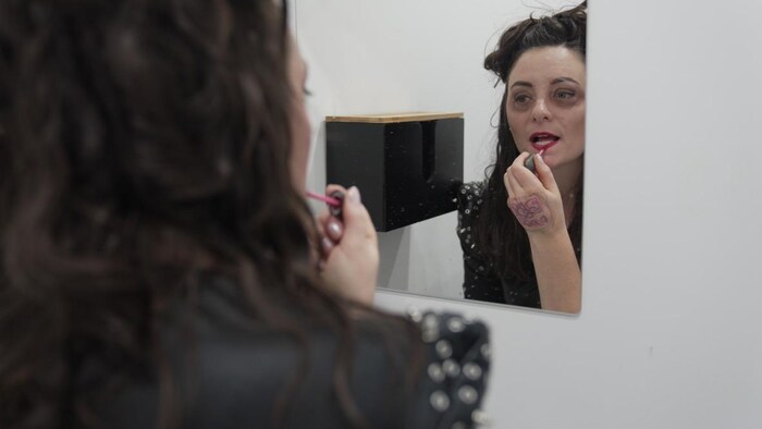 Kimberley Guénette se maquille devant un miroir.