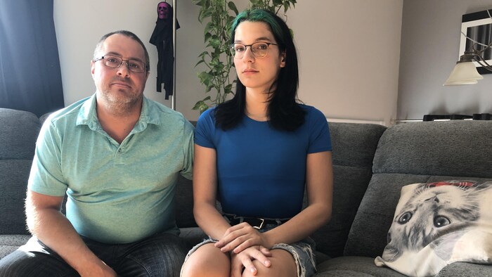 Le père et sa fille assis sur le divan du salon.