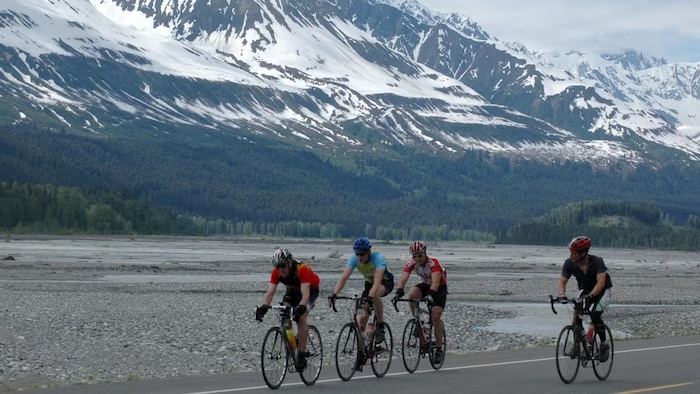Quatre cyclistes avec les montagnes en arrière-plan.