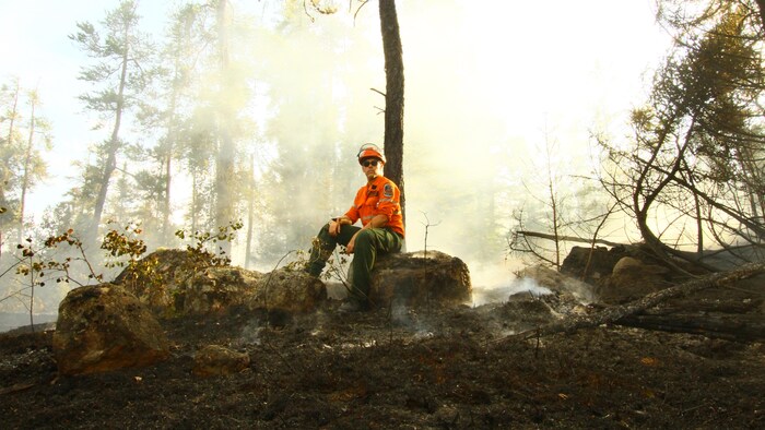 Un sapeur-pompier au repos dans une forêt en feu.