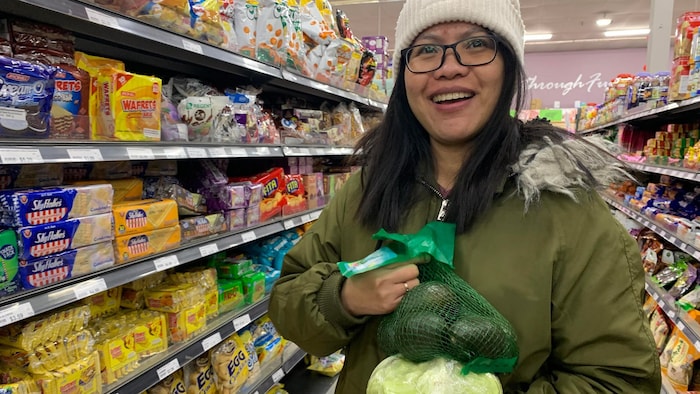 Eden Berou may hawak na avocado at cabbage sa loob ng isang supermarket.