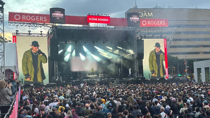 Une foule devant le rappeur sur scène et grand écran. 