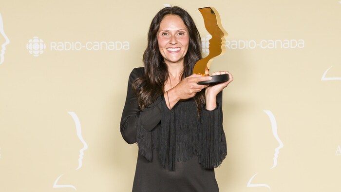 Une femme tient un trophée. 