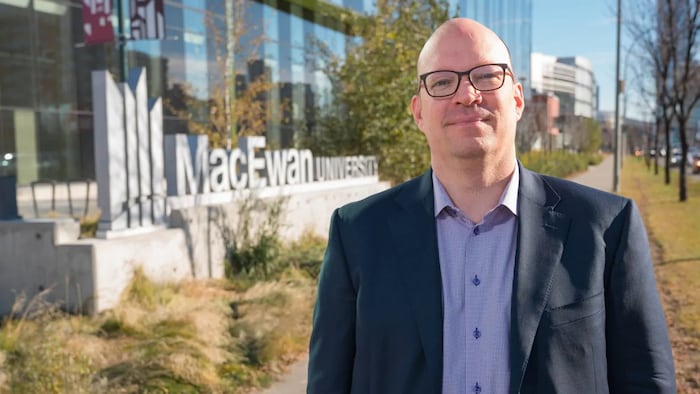 Kristopher Wells pose devant l'Université MacEwen.