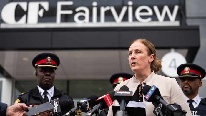 Kristy Smith parle aux médias devant des policiers et le centre commercial.