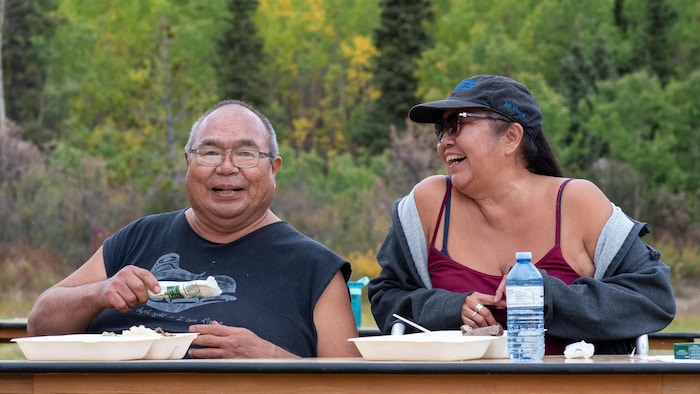 Deux personnes qui sourient en mangeant.