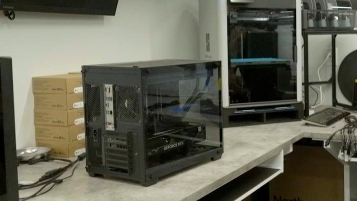 Un ordinateur de jeu, sur une table, à côté d'une imprimante 3D.