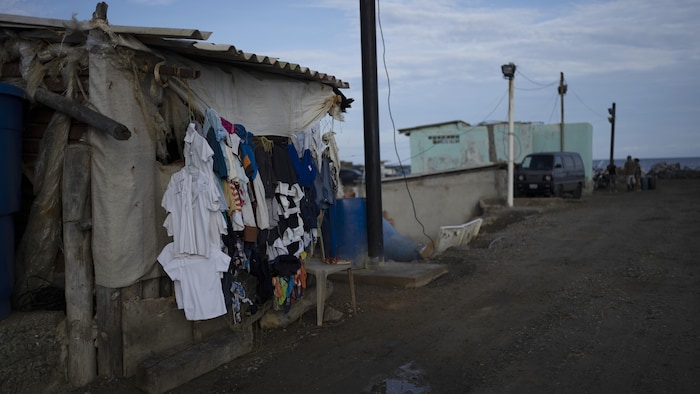 Des vêtements propres sont suspendus pour sécher devant une maison délabrée près d'un port.