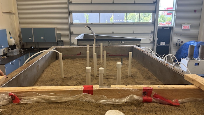 Un laboratoire scientifique avec une cuve qui contient du sable et des tuyaux.