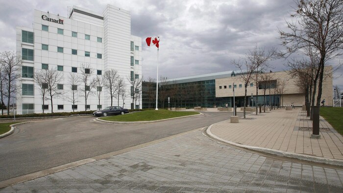 Un édifice où un logo du gouvernement du Canada peut être vu sur la façade. Un drapeau canadien flotte devant l'édifice.