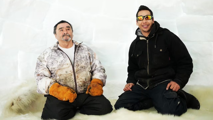 Les deux hommes dans l'igloo sont assis sur une fourrure d'ours polaire.