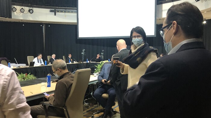 France Bélisle en discussion avec un café à la main et un masque sur le visage.