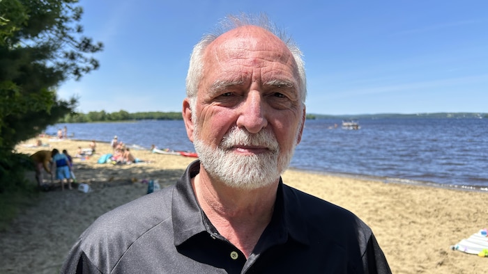 Denis Lalumière regarde la caméra, debout sur la plage.