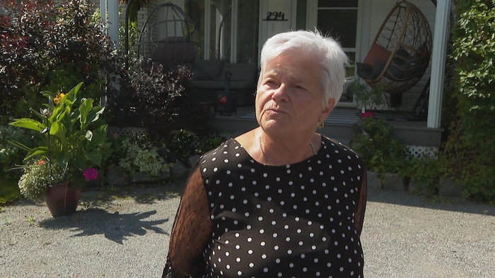 Une dame devant une maison.