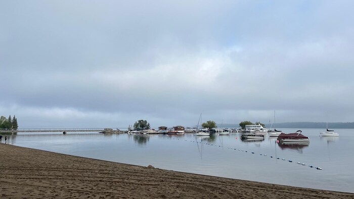 Des voiliers et des bareaux mouillent dans le lac lelong d'un quai, en juillet 2023.