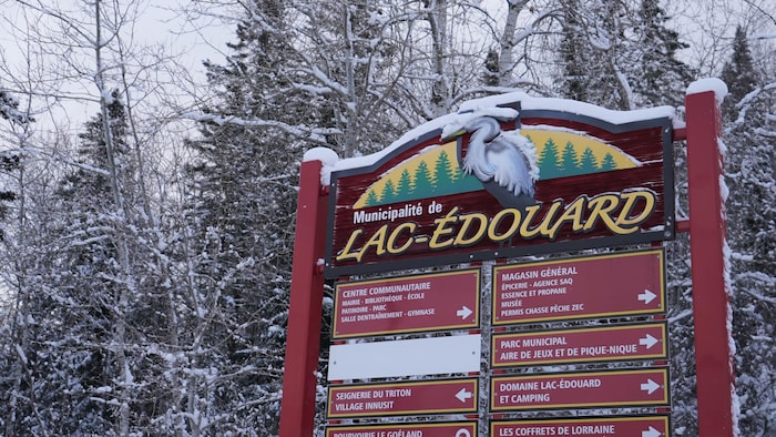 L'affiche indiquant la Municipalité de Lac-Édouard et différents services qui y sont offerts, dans un milieu boisé, en hiver.