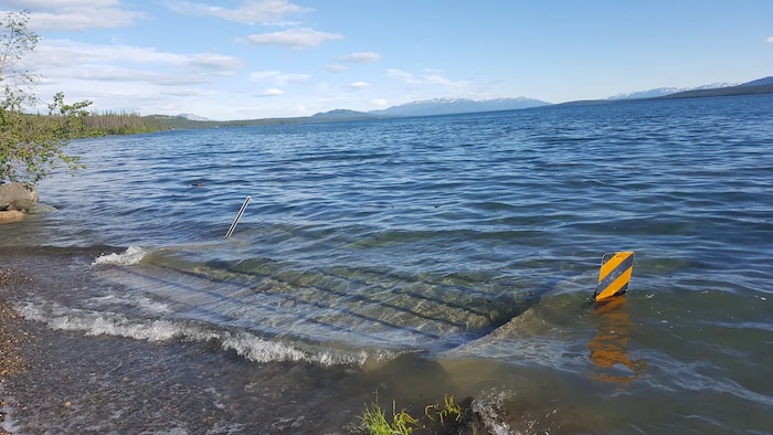 De l'eau submerge un petit bateau à quai sur le lac Marsh, au Yukon.