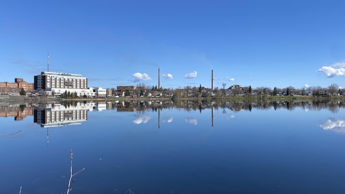 L'Hôpital de Rouyn-Noranda et les cheminées de la Fonderie Horne sont reflétés dans le lac Osisko.