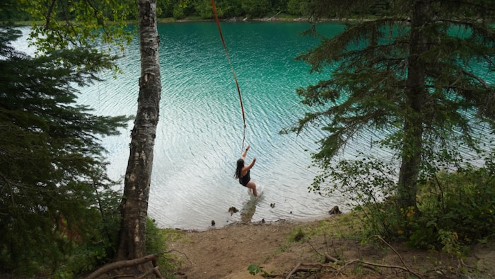 Mylène plonge à l'eau après avoir utilisé une « corde Tarzan ».