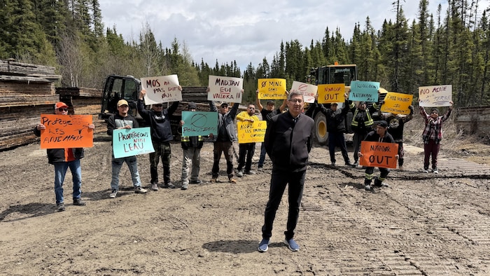Lucien Wabanonik pose avec un groupe de manifestants qui tiennent des pancartes dans un chemin forestier.