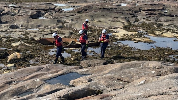 Les équipages sur l'eau récupèrent et transportent les débris dangereux tordus vers les embarcations de la Garde côtière.