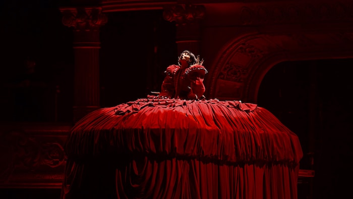 Lady Gaga, portant une large robe, chante sur scène.