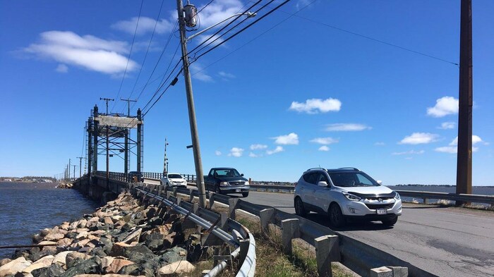 Des voitures sur la route bordée de poteaux électriques neufs