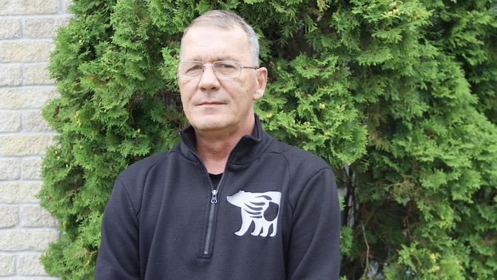 Un homme pose devant un arbre.