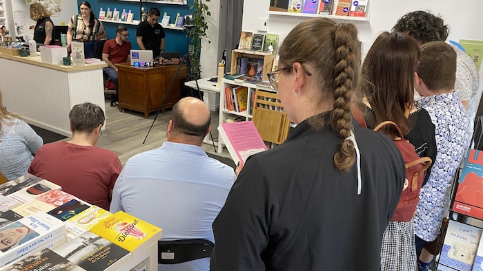 Des participants assis dans une librairie écoutent. 
