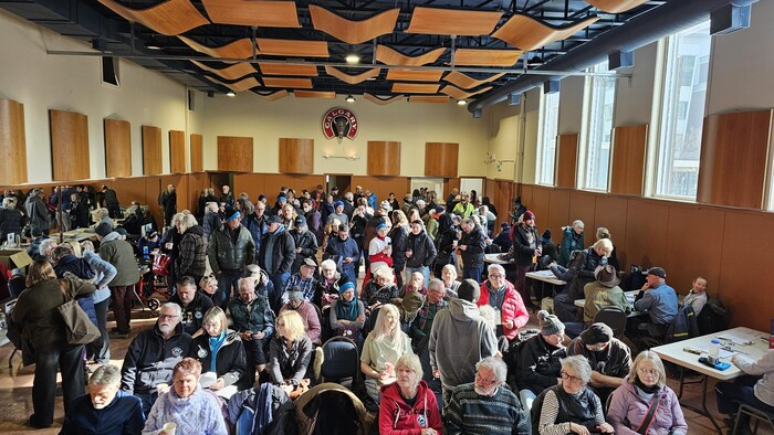 Une salle remplie de personnes assises et debout.