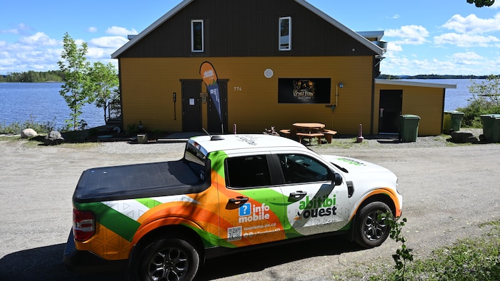 Une camionnette lettrée aux couleurs de la MRC d'Abitibi-Ouest est stationnée devant un bâtiment.