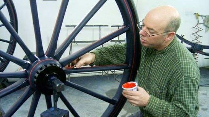 Il imprègne une roue de voiture à cheval d'un liquide rouge.