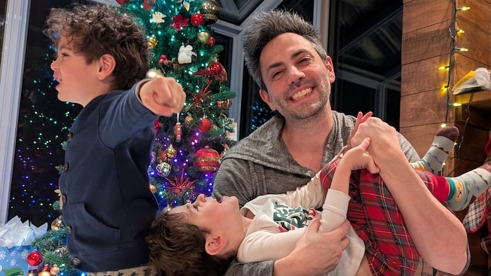 La famille pose devant un sapin de Noël.