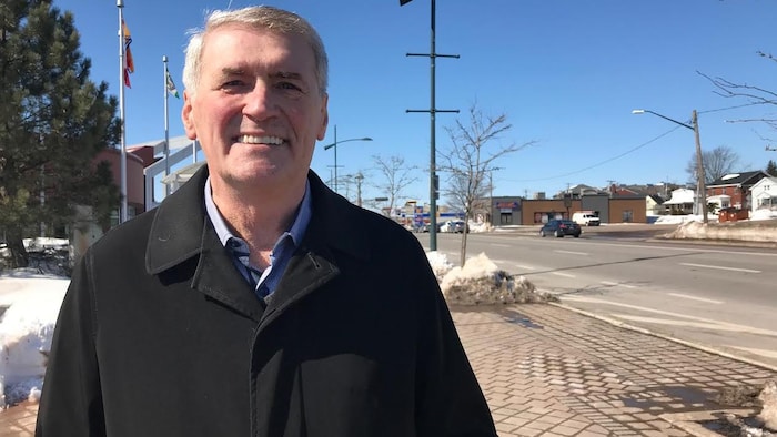 Yvon Lapierre sur un trottoir avec des lampadaires en arrière-plan.
