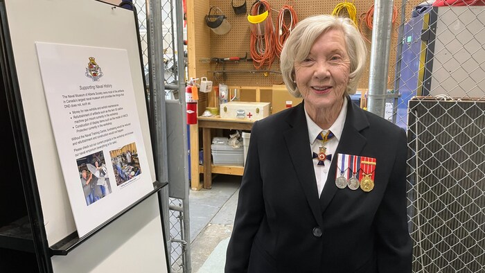 La commodore Laraine Orthlied pose de face en souriant. Elle porte son uniforme de la Marine, agrémenté de plusieurs médailles.