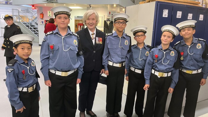 La commodore Orthlieb pose aux côtés de six jeunes cadets en uniforme.