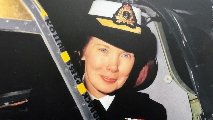 Photo de Laraine Orthlieb souriant à la caméra. Elle porte son uniforme de la Marine, avec une casquette et plusieurs médailles.