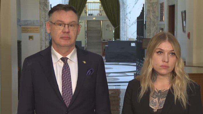 Larry Neufeld et Claire Rattée debout dans un couloir.