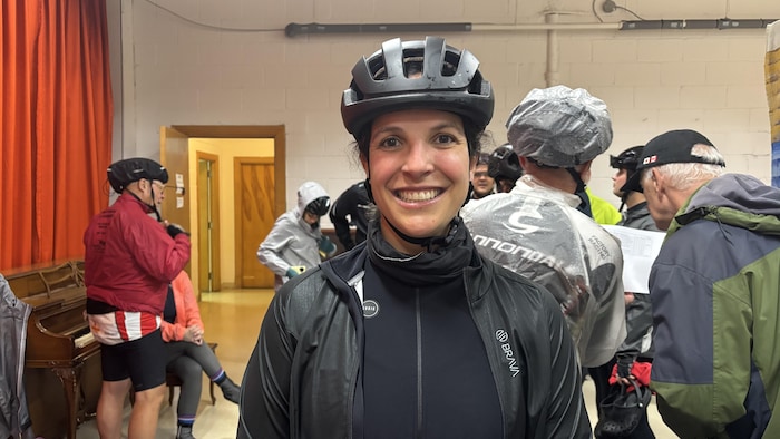 Une femme en habit de cycliste sourit à la caméra.