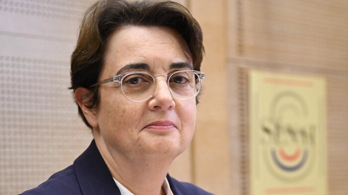 Une femme portant des lunettes regarde l'objectif.