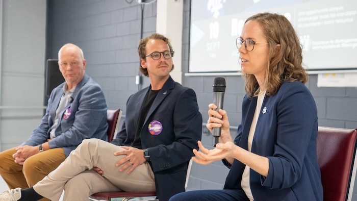 Laurent Bélisle et ses collègues écoutent une intervenante s'exprimer micro en main lors d’une table ronde.