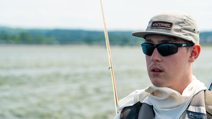 Portrait de Laurent Thériault devant le fleuve, portant des lunettes et une casquette.